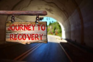 Sign at the end of a tunnel that says "Journey to Recovery"